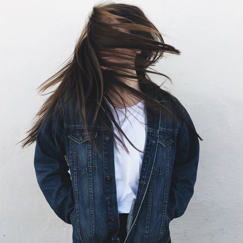 Person with long hair flipping their head in a denim jacket
