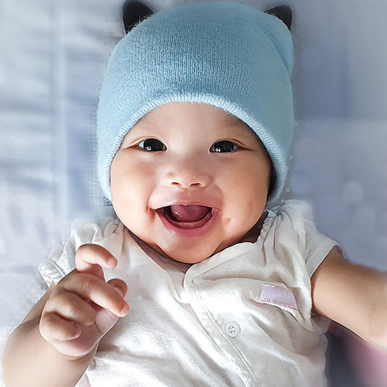 Laughing baby wearing a blue hat