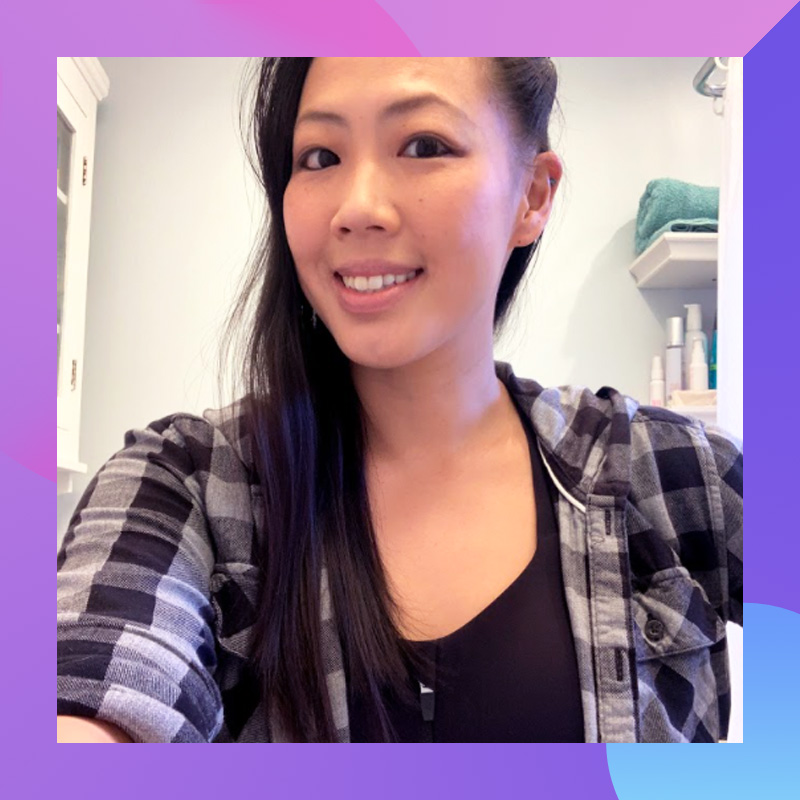 Asian woman wearing a plaid shirt and a sports bra, taking a selfie.