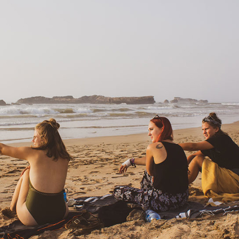 three women on the beach, with the third sitting further away