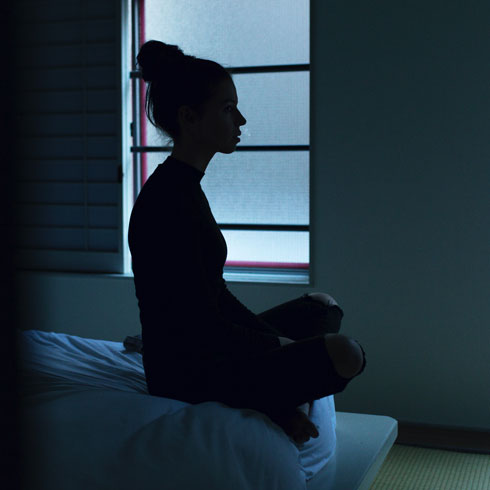 A woman sitting alone on her bed at night
