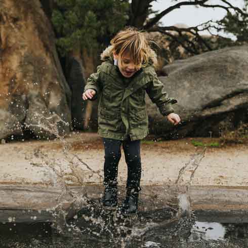 A little boy on his own jumping in puddles