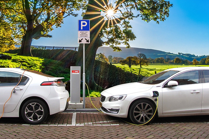 Two white electric cars at an outdoor charging station