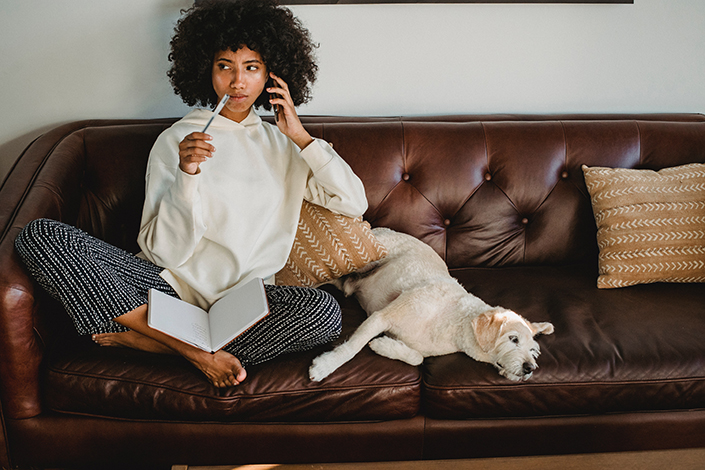 Woman sitting on the couch with a journal open, next to her dog