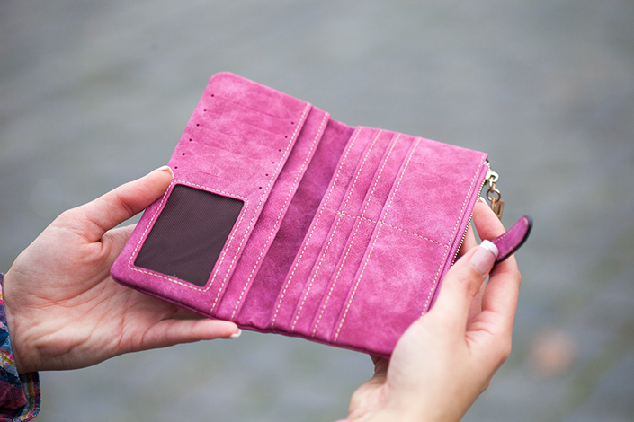 Person opening up a pink suede wallet
