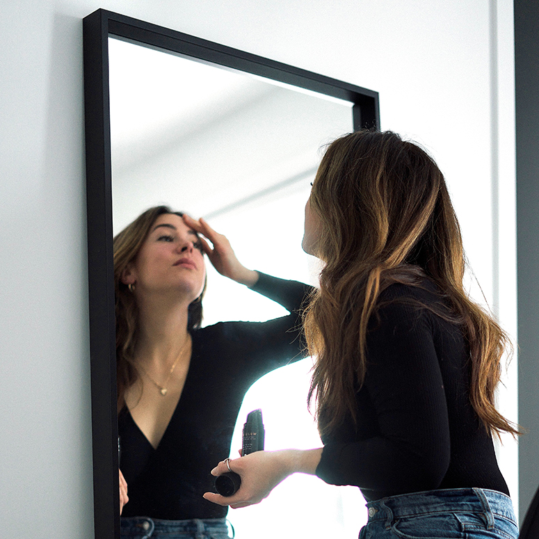 Person looking at herself in the mirror, with hand to forehead