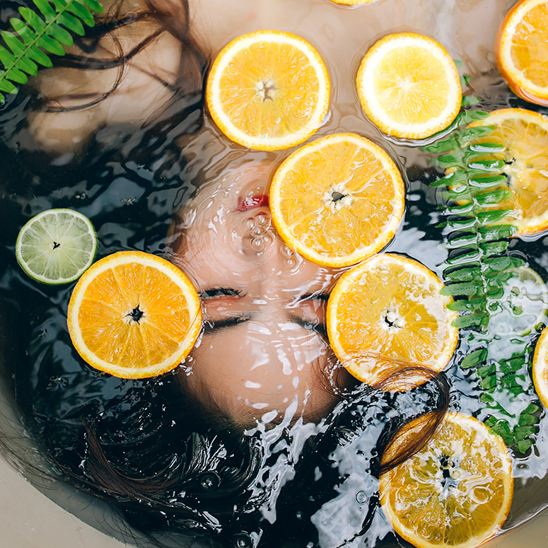 Woman in a bath of citrus and ferns