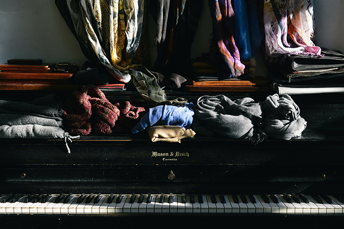 stacks of clothing on an old black grand piano