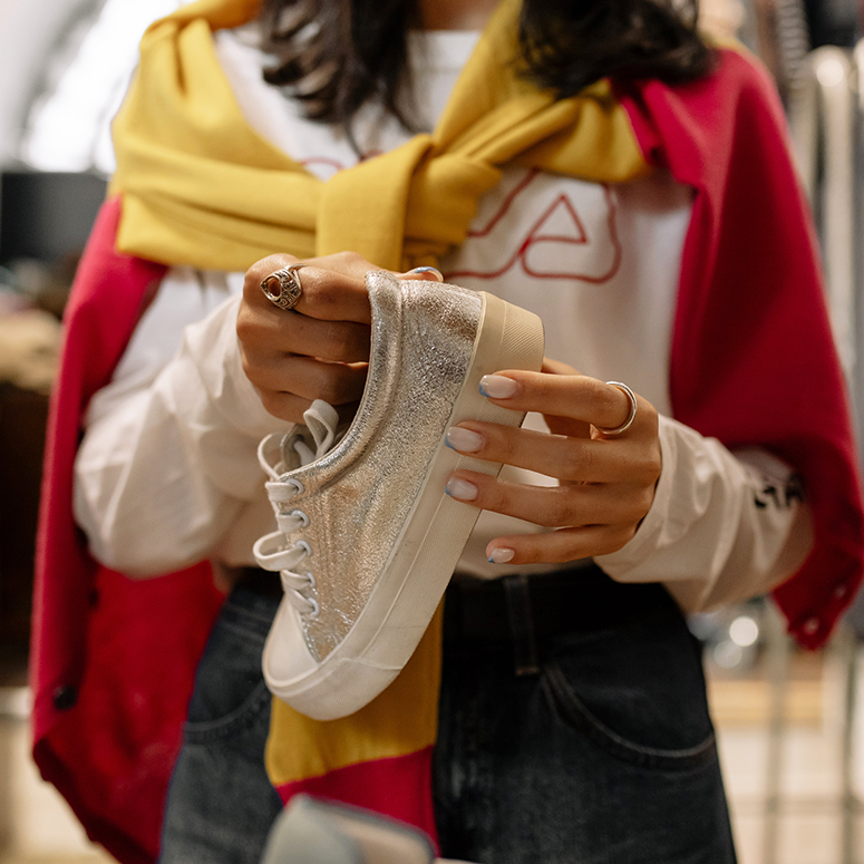a woman with manicured hands hold a shoe in a clothing store