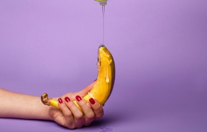 A hand holding a banana, covered in lubricant 