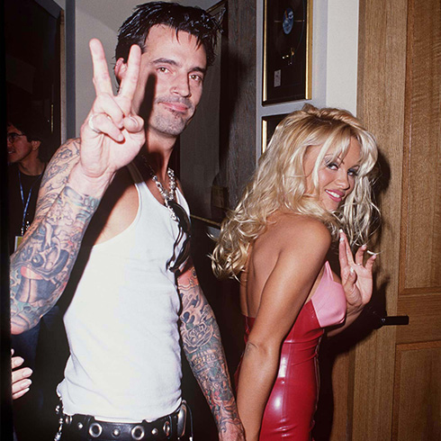 Tommy Lee showing a peace sign and holding hands with Pamela Anderson