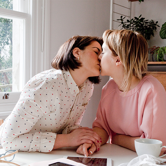 Two women kissing in a kitchen