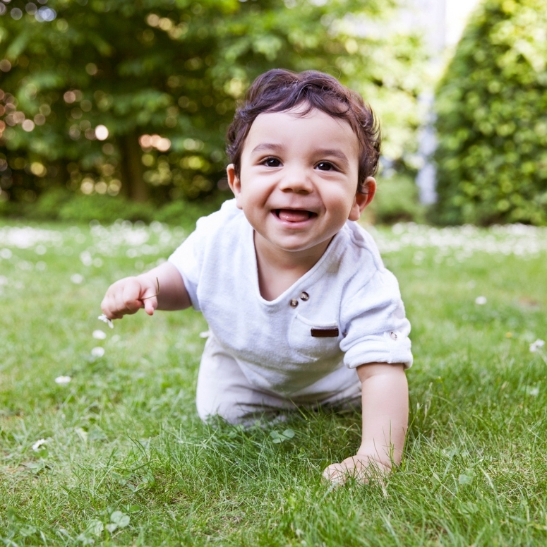 Baby smiling and crawling in the grass