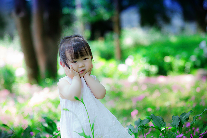 a young Asian toddler in a dress outside in nature