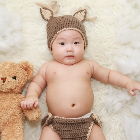 Baby wearing deer hat holding a bear.