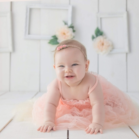 Baby wearing a pink dress smiling.