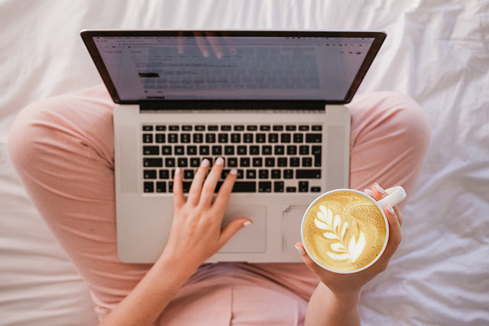 Woman working away at her laptop in her jammies and a latte