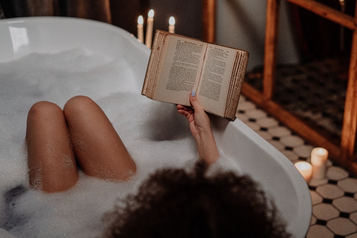 A woman reading a book in a bubble bath