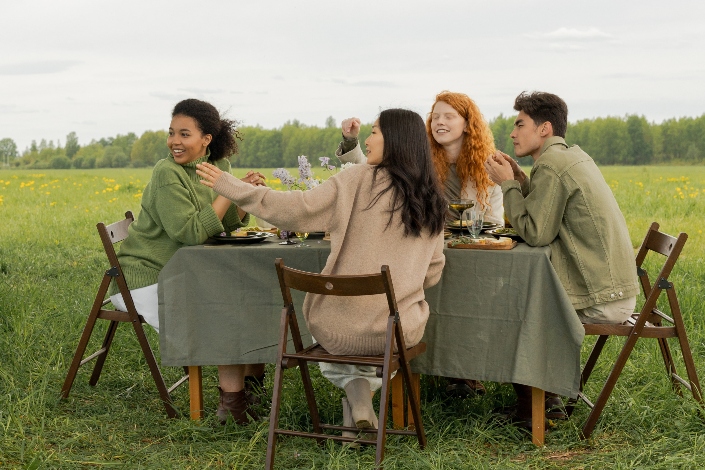 Four friends eating a meal in a field outdoors