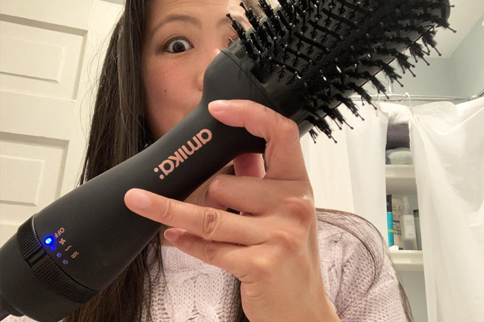 Asian woman tests hair dryer brush