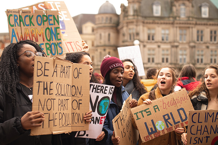 a group of young women holding up climate change signs