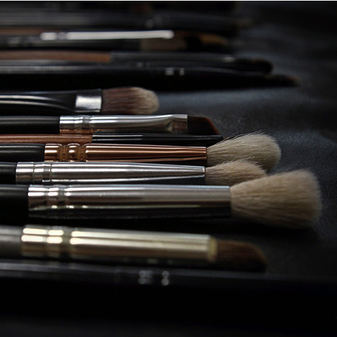 Close up of a variety of makeup brushes lying on a black cloth.