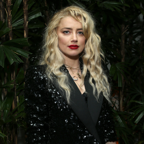 Amber Heard wearing a black suit jacket and red lipstick