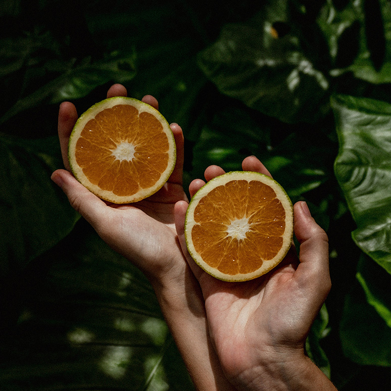 Hands holding half oranges