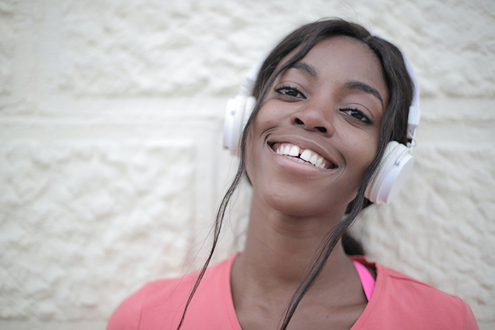a young Black woman smiling with headphones on