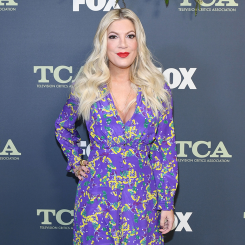 Tori Spelling wearing a long sleeve floral print dress in purple, green and yellow