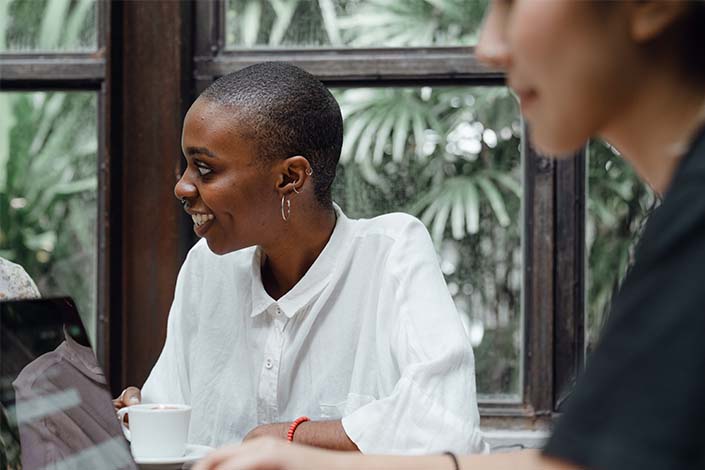 young Black woman wearing white shirt sitting in meeting at work