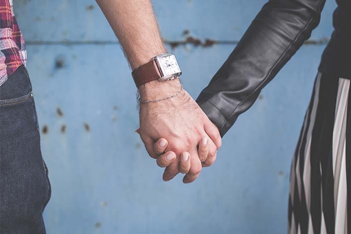 two people holding hands, one with a watch on the wrist and one with a black sleeve