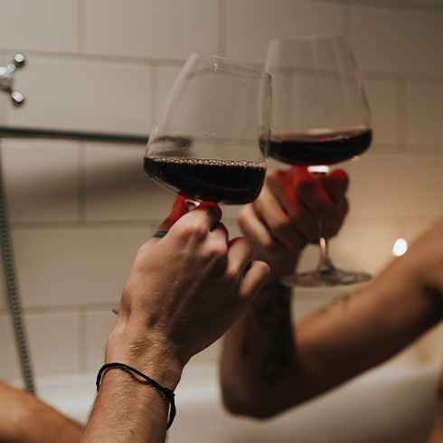 Two people raising a glass of wine in bathtub