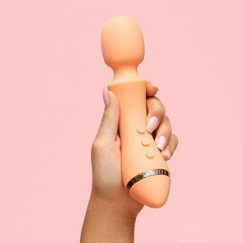 Hand holding a peach coloured Vush Vibrator