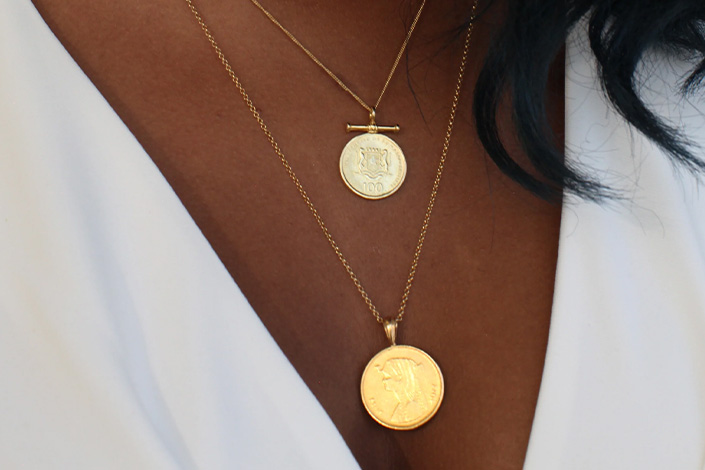 Close up of woman wearing two gold necklaces from Omi Woods