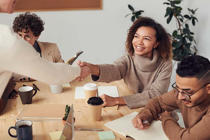 Young Black woman shaking hands in a business meeting.