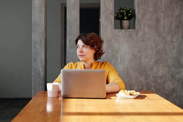 Woman sitting alone at a table with a laptop of her
