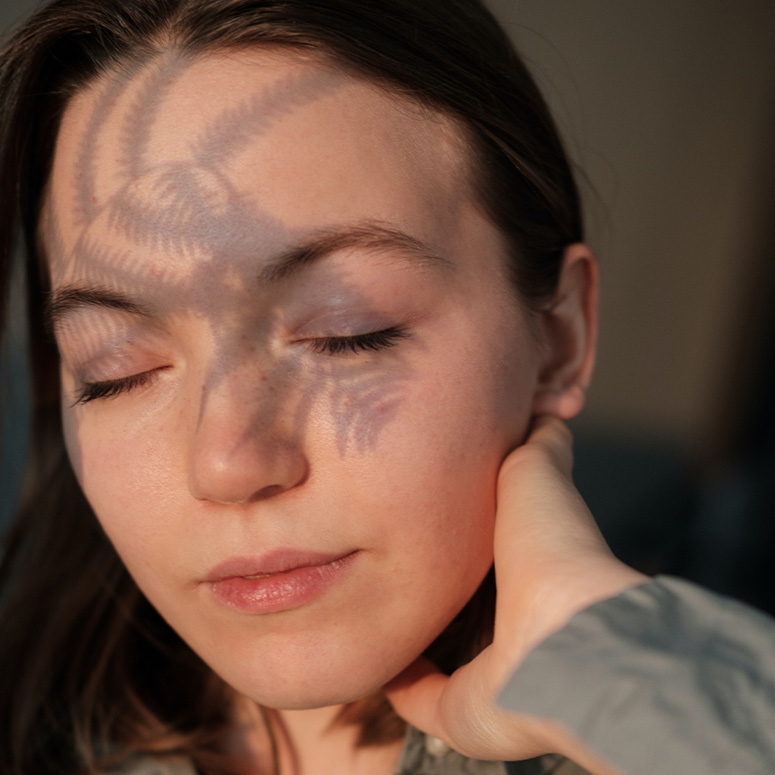 Close up of woman's face with a shadow of a plant on her face