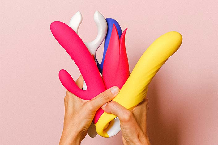 white hands holding colourful sex toys