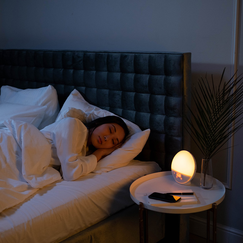 Woman sleeping in a dark room with an ambient light on.