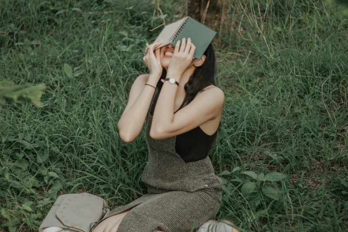 Girl sitting in grass with her head in a book