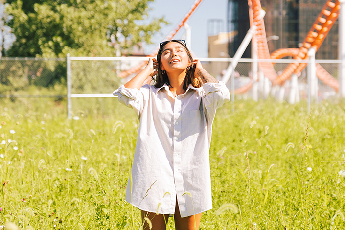 Girl in long white dress shirt in the grass staring up at the sky