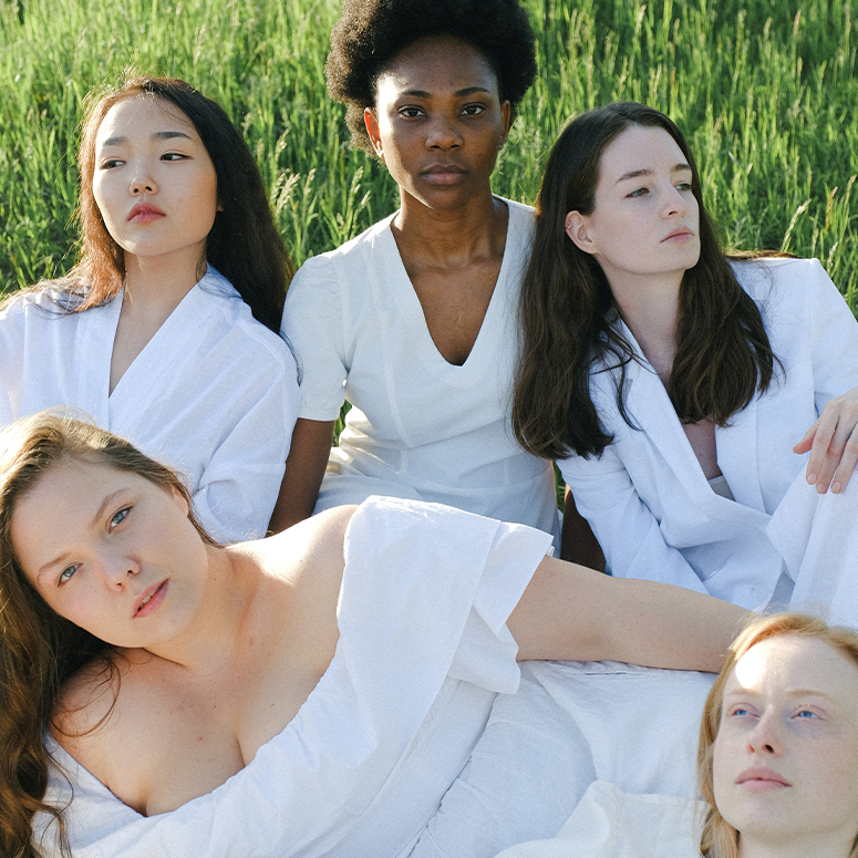 Four women all wearing white in a field