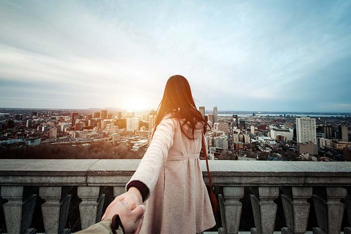 woman holding someone's hand while looking out at view