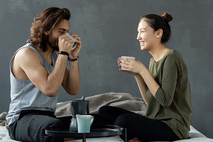 Man and woman drinking coffee on bed