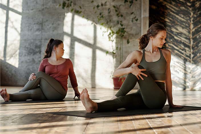 Two young woman stretching on yoga mats