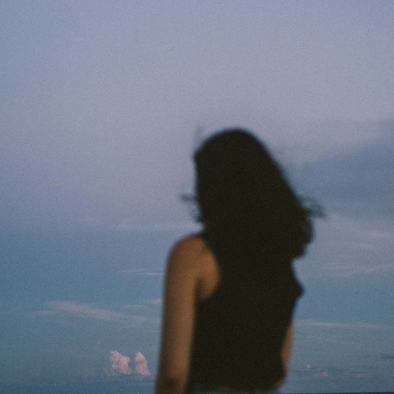 slightly blurry image of woman with dark hair looking into distance