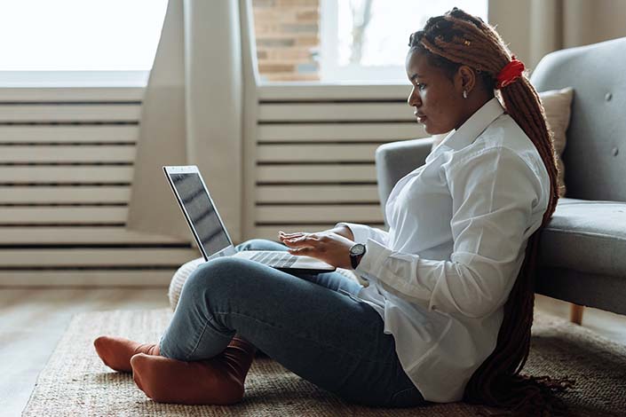 Woman sitting on floor working on her laptop