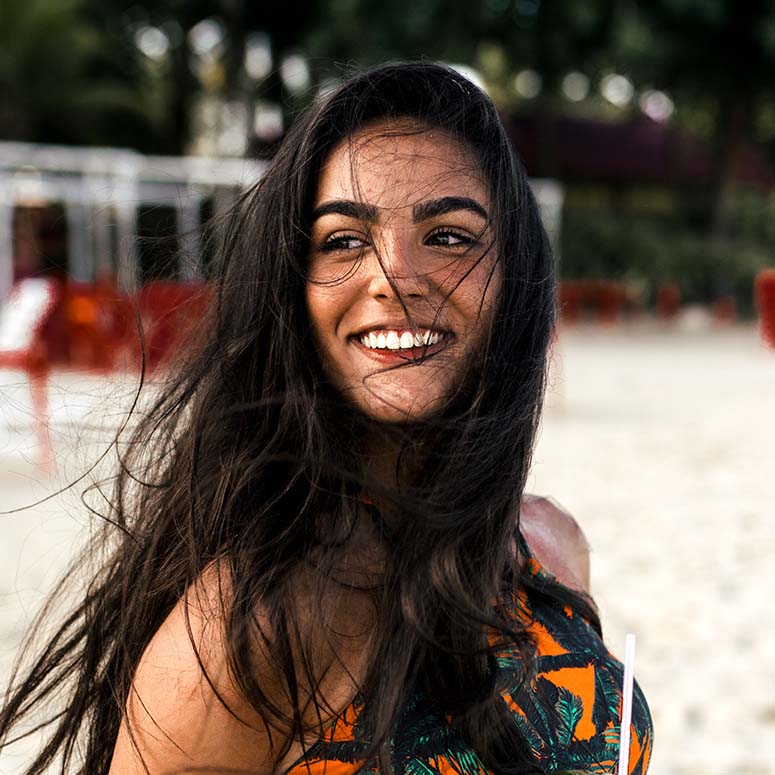 Woman smiling on beach with hair blowing around her