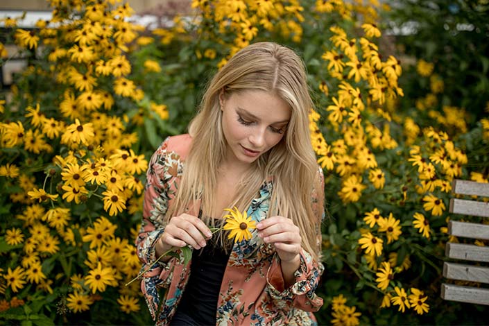 Young blonde woman standing in a field of yellow daisies